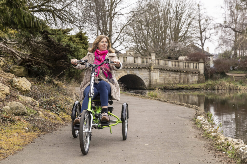 Vrouw met hernia fiets op een elektrische driewieler.