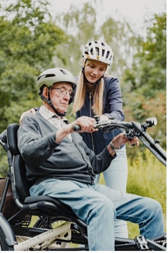 Een oudere man die oefent met wegrijden op een driewieler.